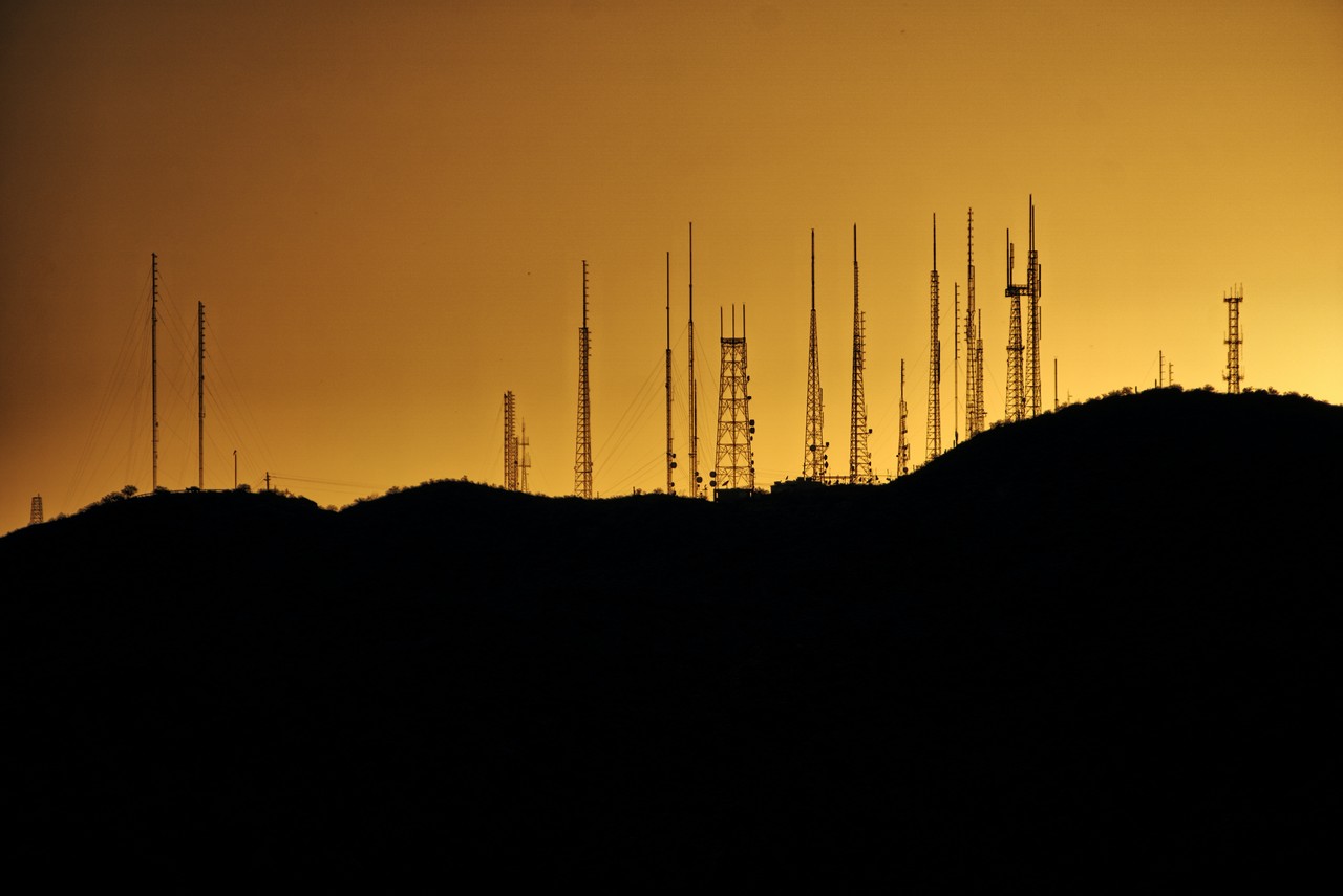 curso de telecomunicações - morro com antenas sob um céu alaranjado 